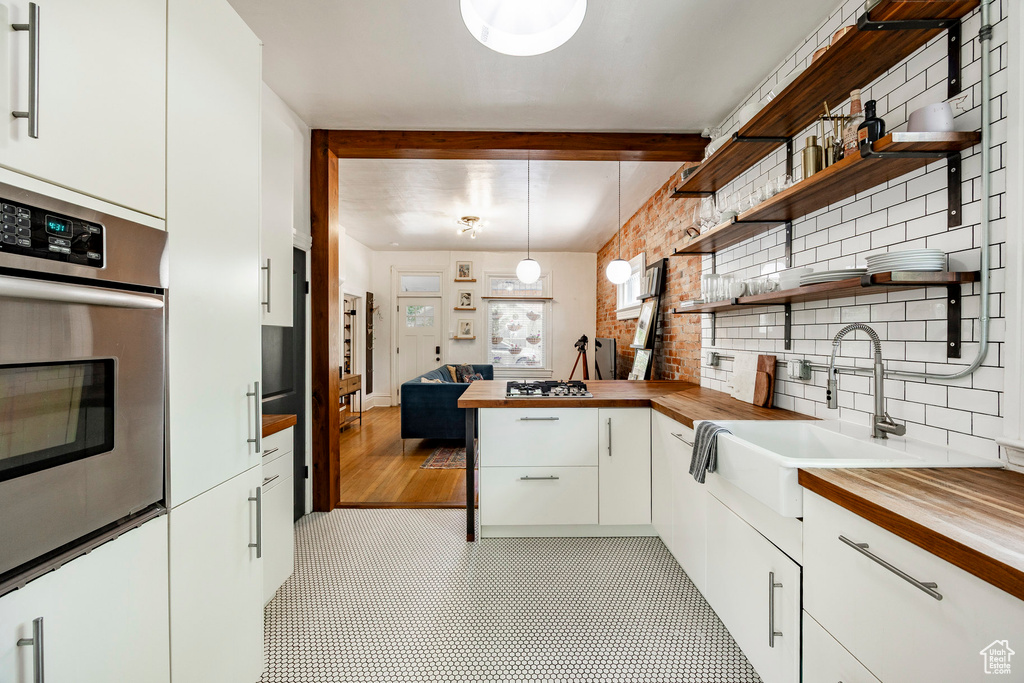 Kitchen featuring wooden counters, oven, open shelves, and white cabinetry