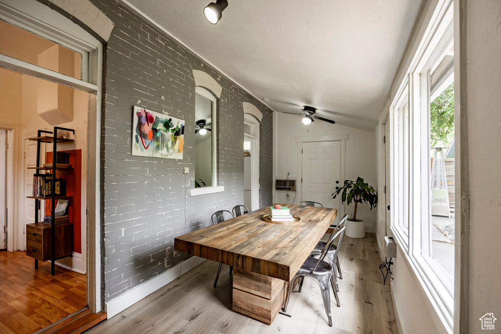 Dining space with wood finished floors, ceiling fan, and vaulted ceiling