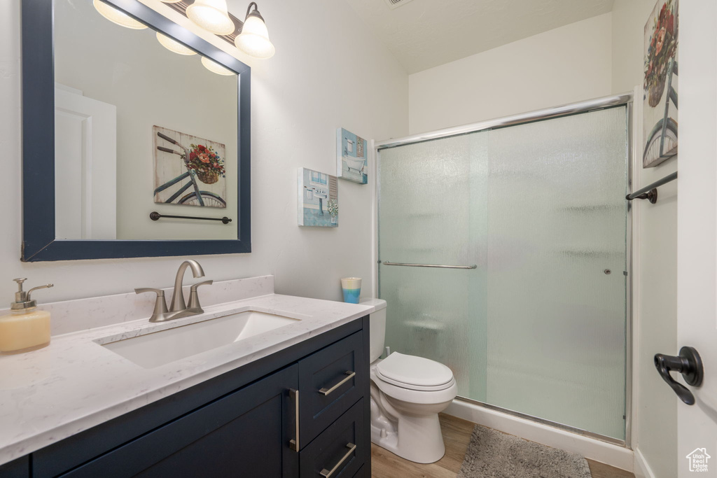 Full bath with vanity, a shower stall, and wood finished floors