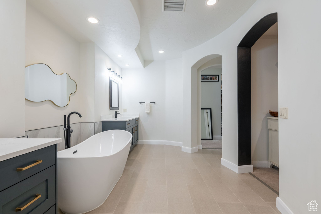 Full bath with vanity, a freestanding bath, recessed lighting, and tile patterned floors