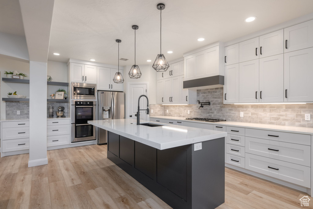 Kitchen with stainless steel appliances, open shelves, backsplash, light countertops, and white cabinets