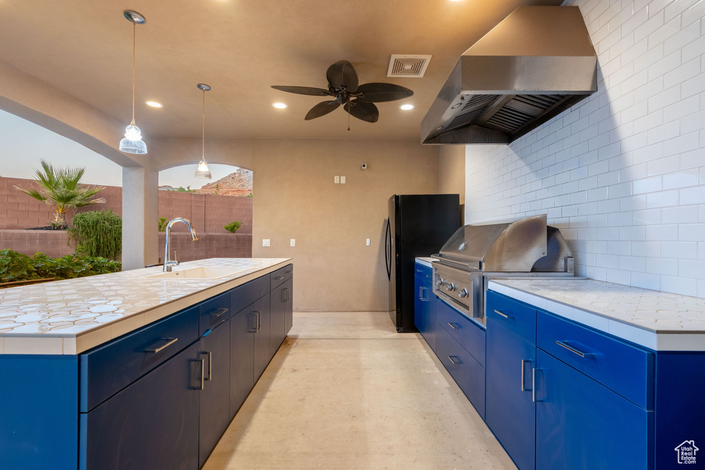 Kitchen with range hood, blue cabinets, tasteful backsplash, light countertops, and recessed lighting