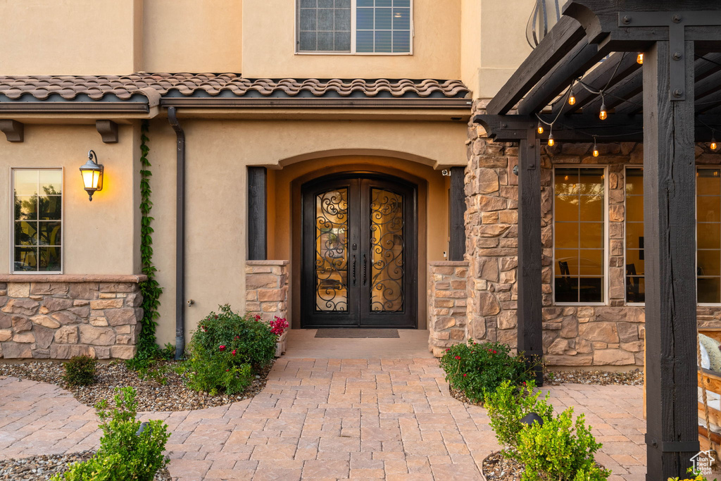 Doorway to property with french doors, stone siding, and stucco siding