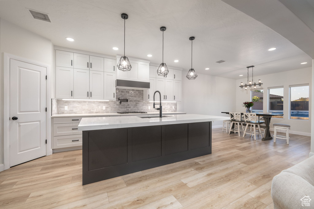 Kitchen with light countertops, backsplash, white cabinetry, light wood-style floors, and recessed lighting