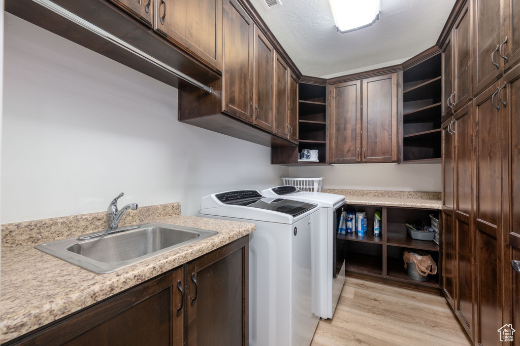 Washroom with washer and dryer, cabinet space, and light wood-type flooring