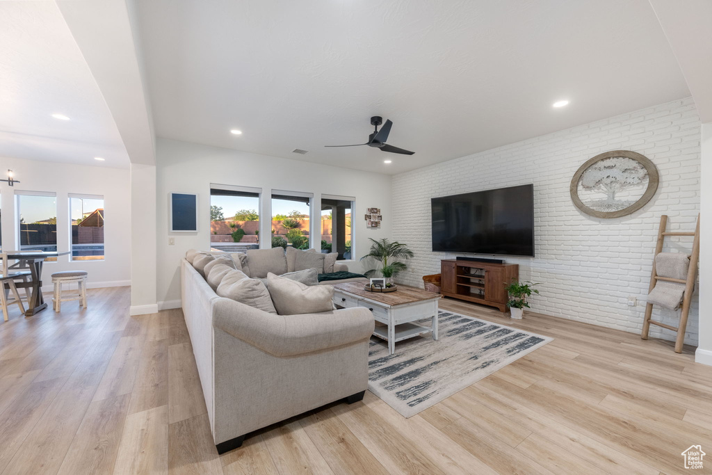 Living room with brick wall, a ceiling fan, wood finished floors, and recessed lighting