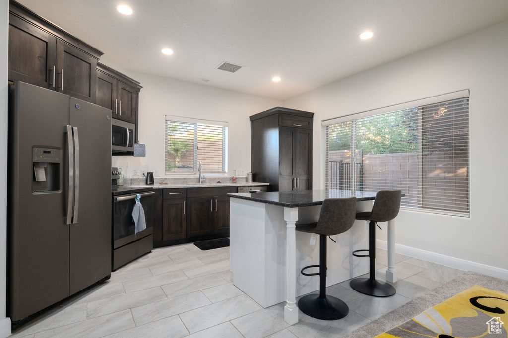 Kitchen with stainless steel appliances, plenty of natural light, a kitchen bar, a kitchen island, and recessed lighting