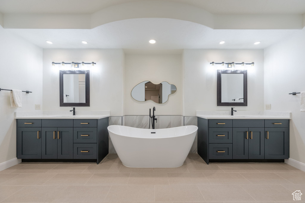 Bathroom with two vanities, a freestanding tub, recessed lighting, and tile patterned flooring