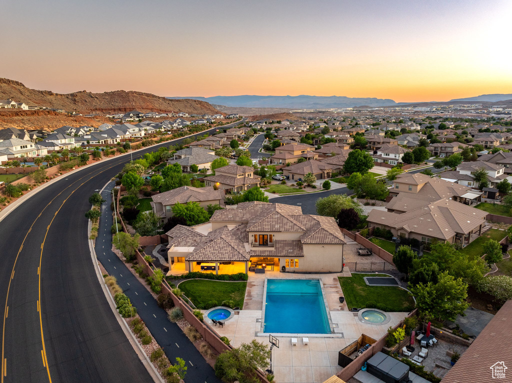 Aerial perspective of suburban area featuring a pool and a mountainous background