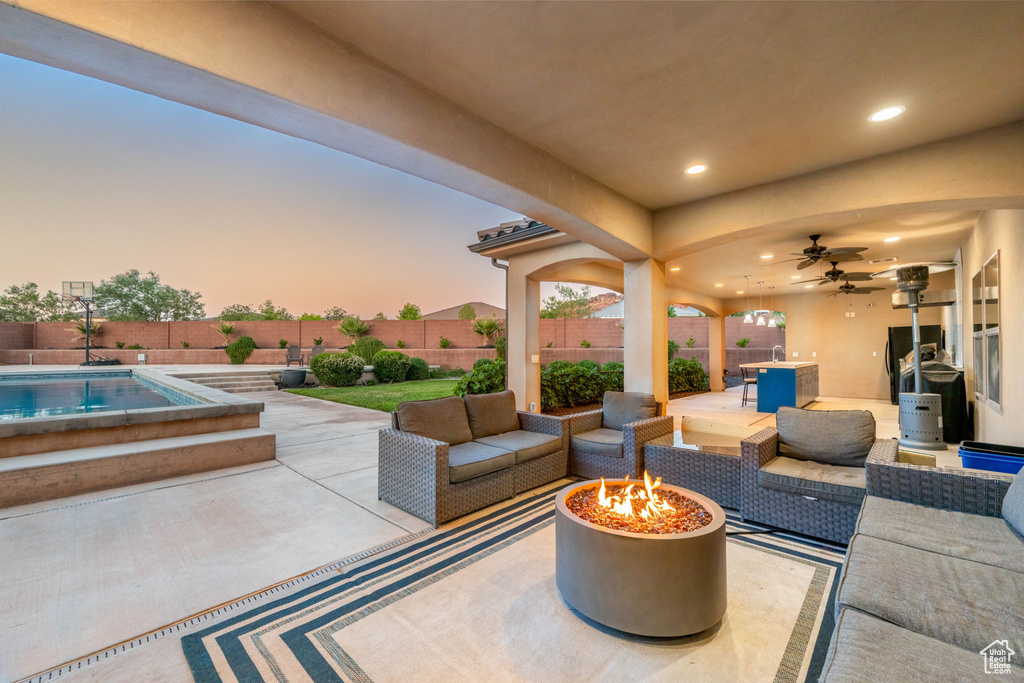Fenced backyard featuring a patio, a ceiling fan, and an outdoor living space with a fire pit