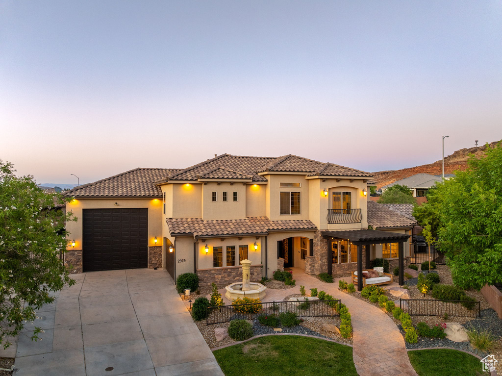 Mediterranean / spanish-style house featuring stone siding, driveway, a balcony, and stucco siding