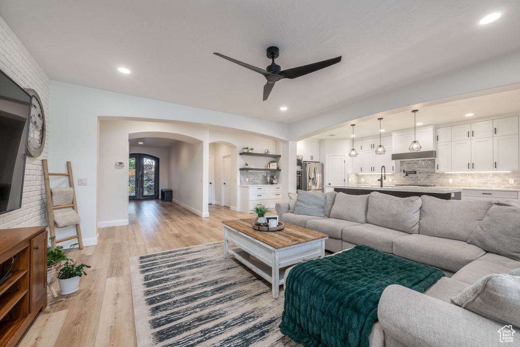 Living area with arched walkways, ceiling fan, light wood-style flooring, and recessed lighting