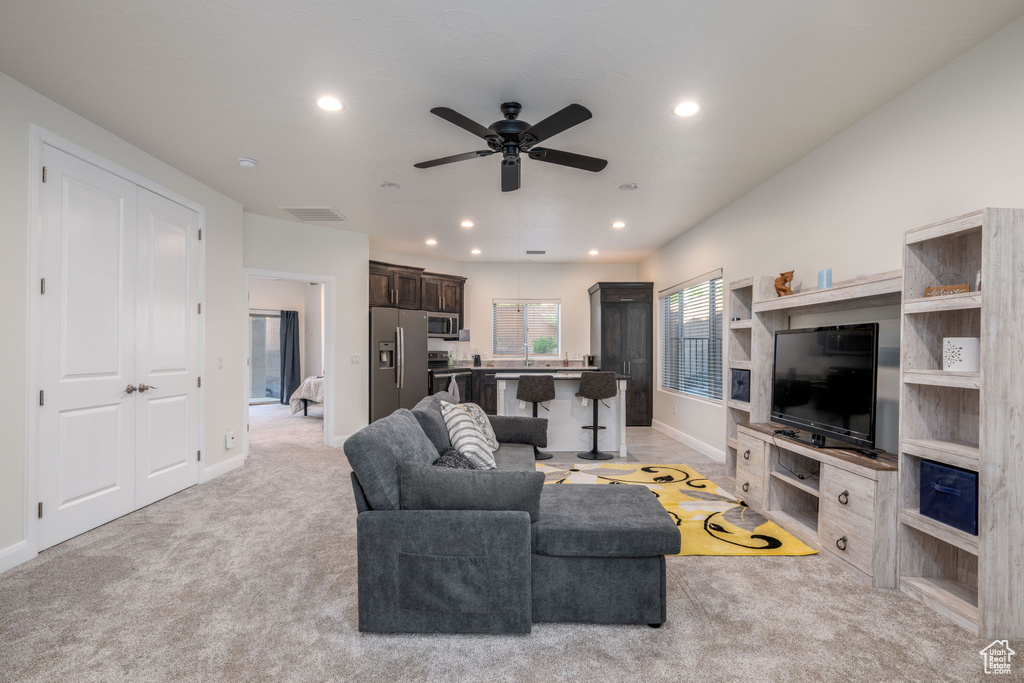 Living area with ceiling fan, recessed lighting, and light colored carpet