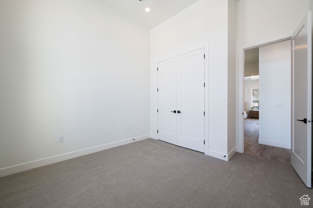 Unfurnished bedroom with carpet, a high ceiling, and recessed lighting