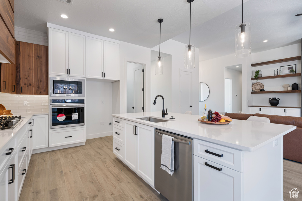 Kitchen featuring stainless steel appliances, light wood-style floors, light countertops, decorative backsplash, and recessed lighting