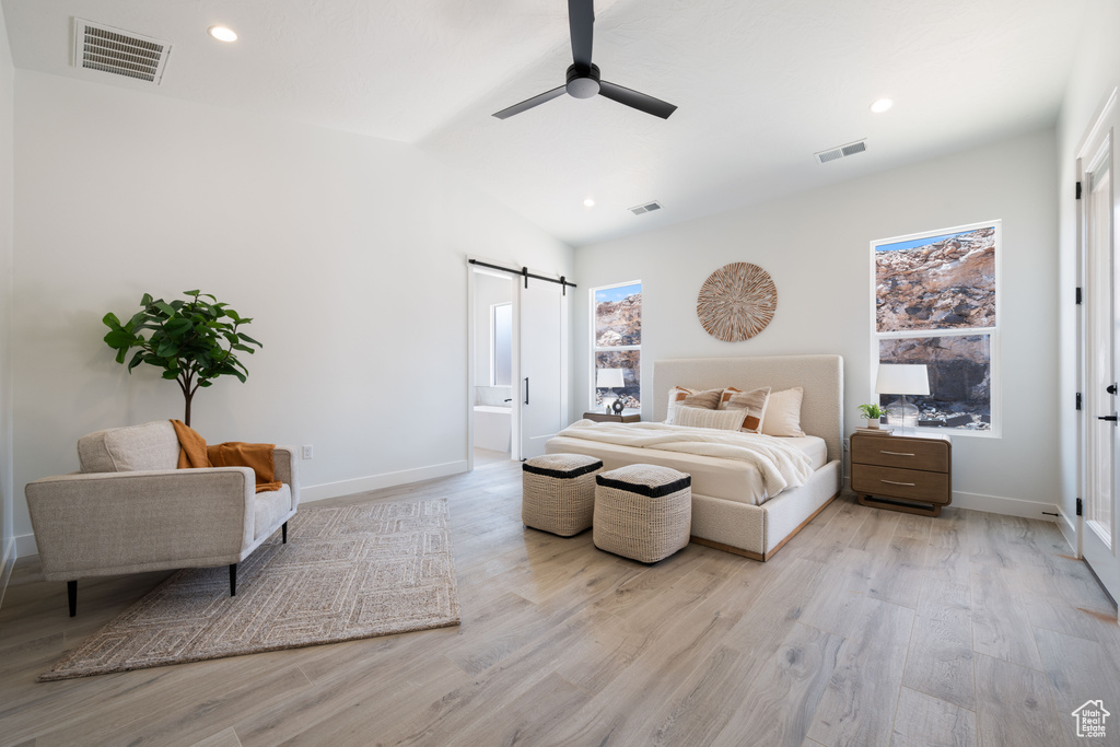 Bedroom with a barn door, light wood-style flooring, recessed lighting, a ceiling fan, and vaulted ceiling