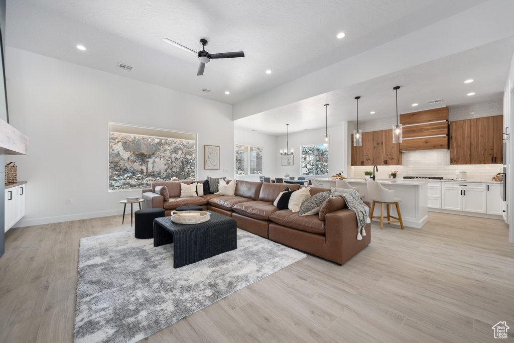 Living area featuring recessed lighting, ceiling fan, light wood finished floors, and a chandelier