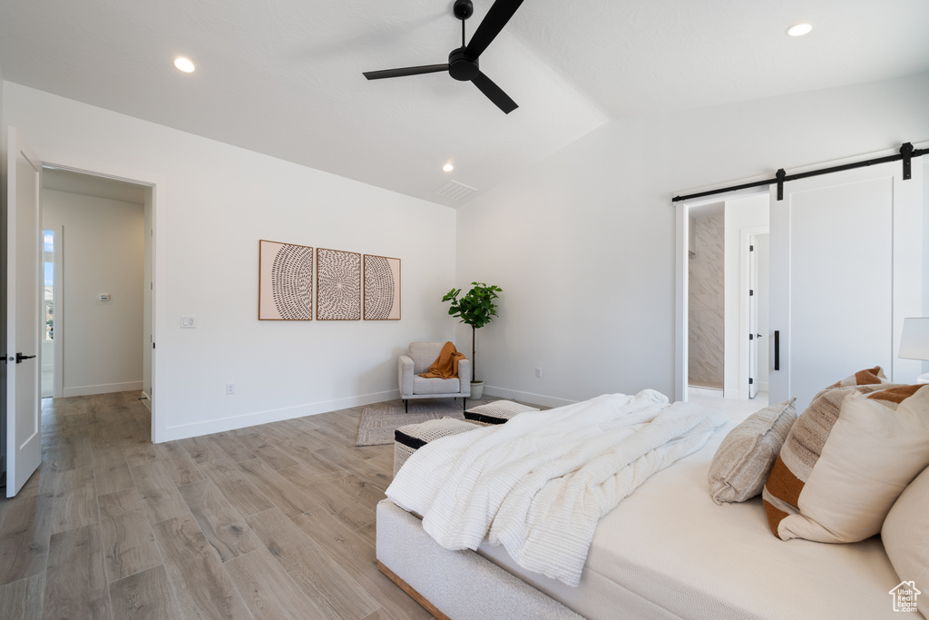 Bedroom featuring a barn door, lofted ceiling, recessed lighting, light wood finished floors, and a ceiling fan