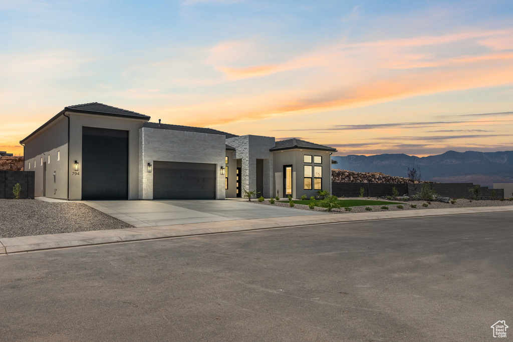 Contemporary house with an attached garage, a mountain view, driveway, and stucco siding