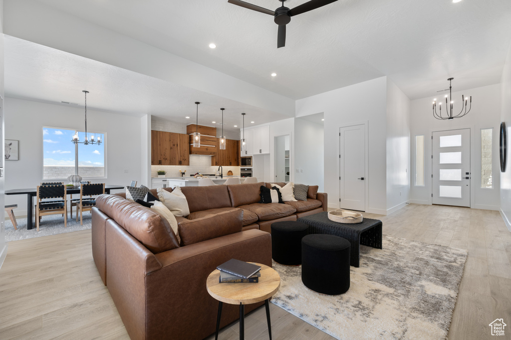 Living room with a chandelier, a ceiling fan, light wood-type flooring, and recessed lighting