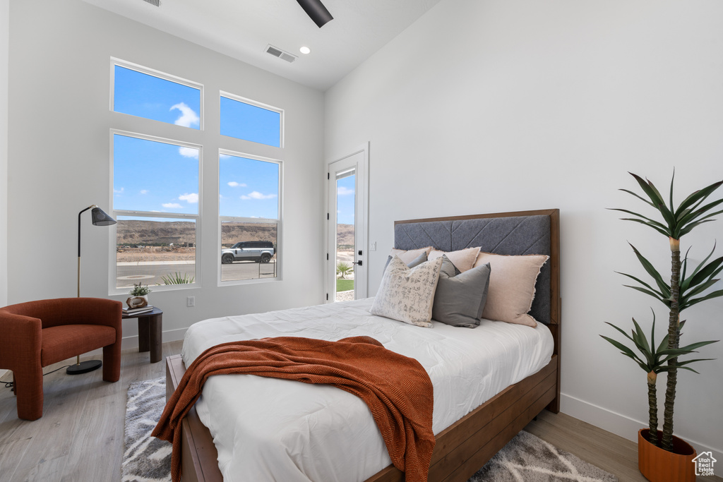 Bedroom with wood finished floors, a high ceiling, and a ceiling fan