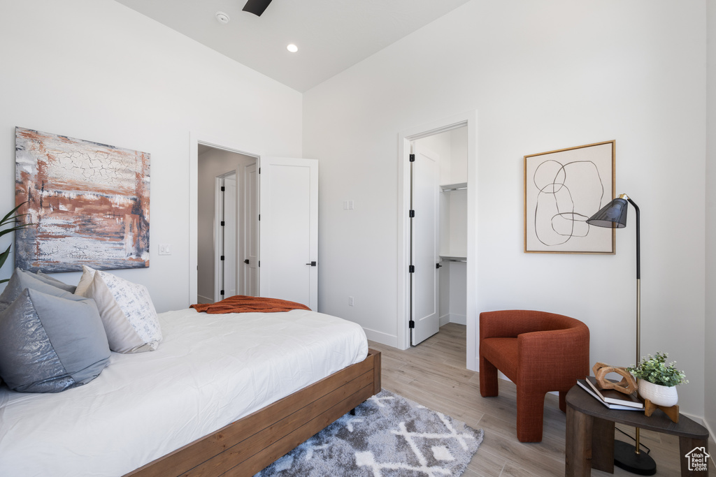 Bedroom featuring light wood finished floors, a walk in closet, a towering ceiling, and a closet