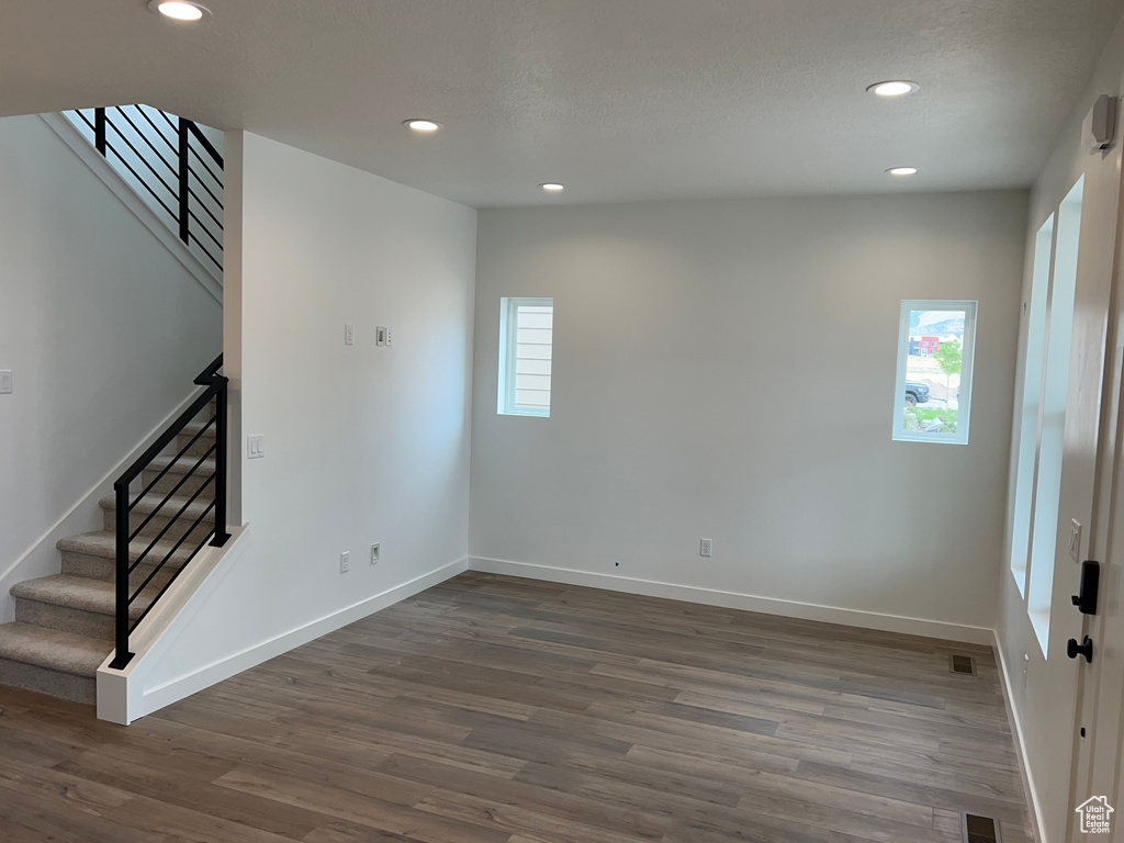 Empty room with stairway, recessed lighting, and dark wood-style flooring