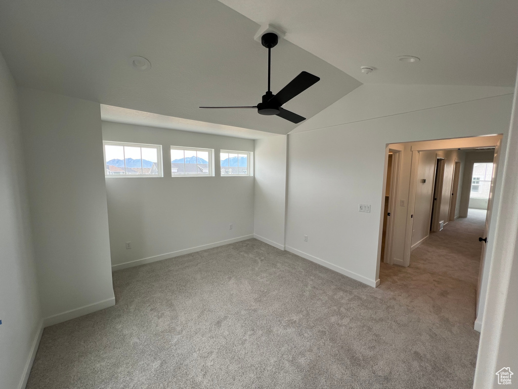 Spare room featuring a ceiling fan, carpet flooring, and lofted ceiling