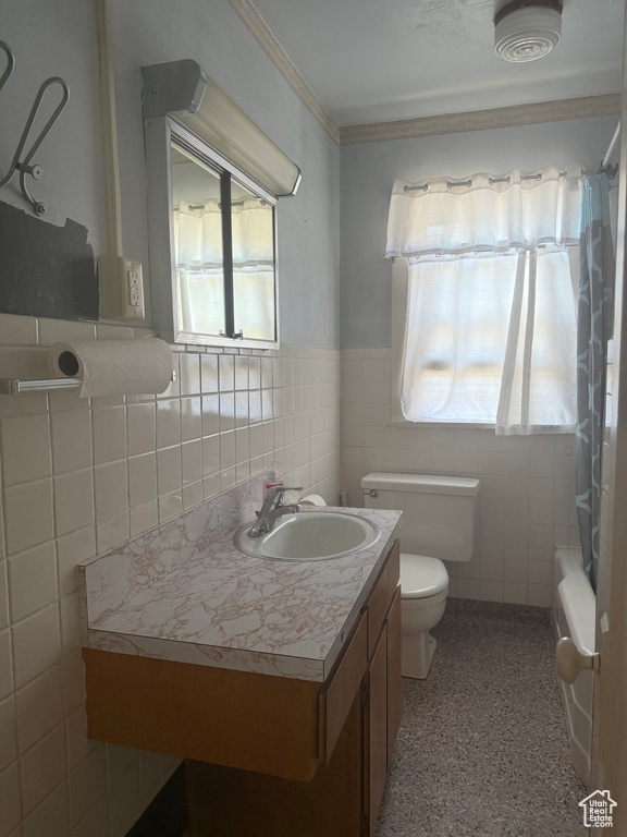 Full bathroom with plenty of natural light, tile walls, vanity, speckled floor, and shower / bath combo