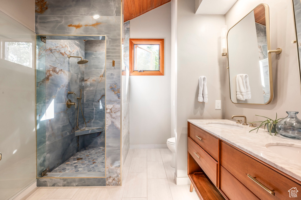 Bathroom featuring double vanity, a walk in shower, and tile patterned flooring