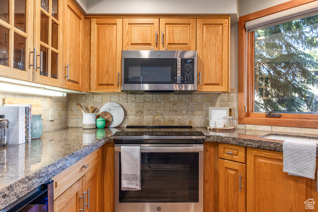Kitchen with stainless steel appliances, glass insert cabinets, and brown cabinets