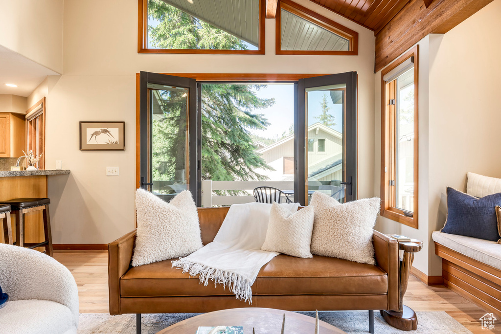 Living room with light wood-style floors, wooden ceiling, and high vaulted ceiling