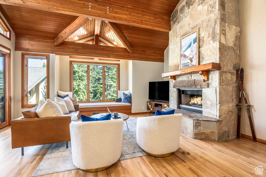 Living area featuring wooden ceiling, a stone fireplace, and wood finished floors