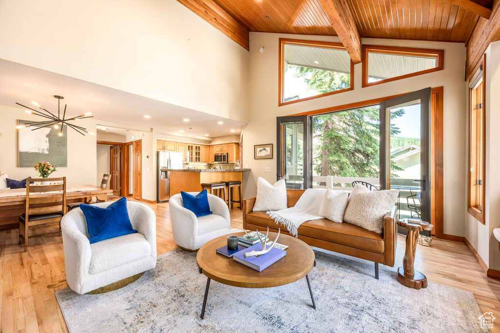 Living area featuring a wooden ceiling with exposed beams, light wood finished floors, a chandelier, and a high ceiling