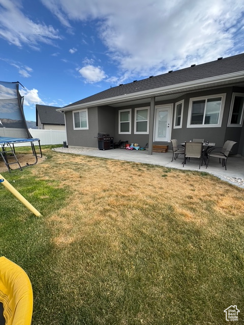 Back of house with a trampoline, a patio area, and stucco siding