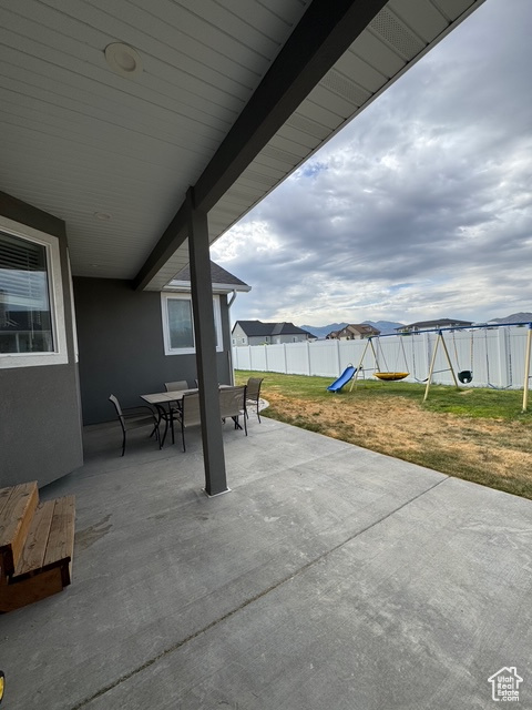 Fenced backyard featuring a playground, outdoor dining space, and a patio area