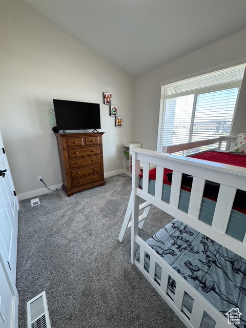 Carpeted bedroom featuring lofted ceiling and baseboards