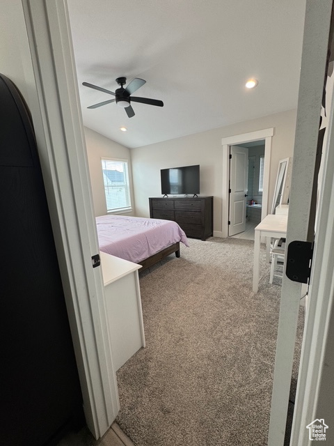 Carpeted bedroom featuring lofted ceiling, recessed lighting, a ceiling fan, and ensuite bathroom