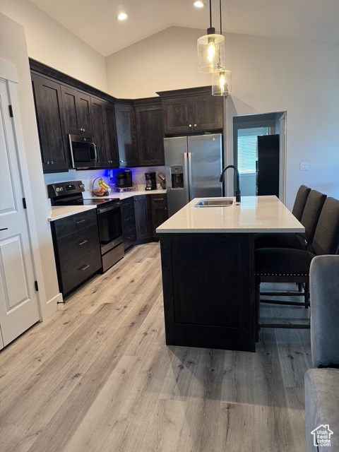 Kitchen with appliances with stainless steel finishes, light countertops, lofted ceiling, light wood-type flooring, and recessed lighting