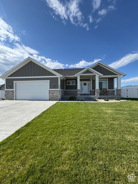 Craftsman house with stone siding, board and batten siding, an attached garage, a porch, and driveway