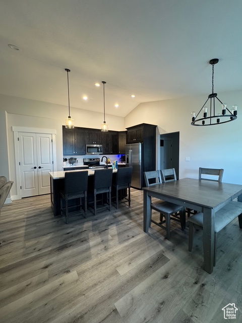 Dining area with a chandelier, light wood-style flooring, vaulted ceiling, and recessed lighting