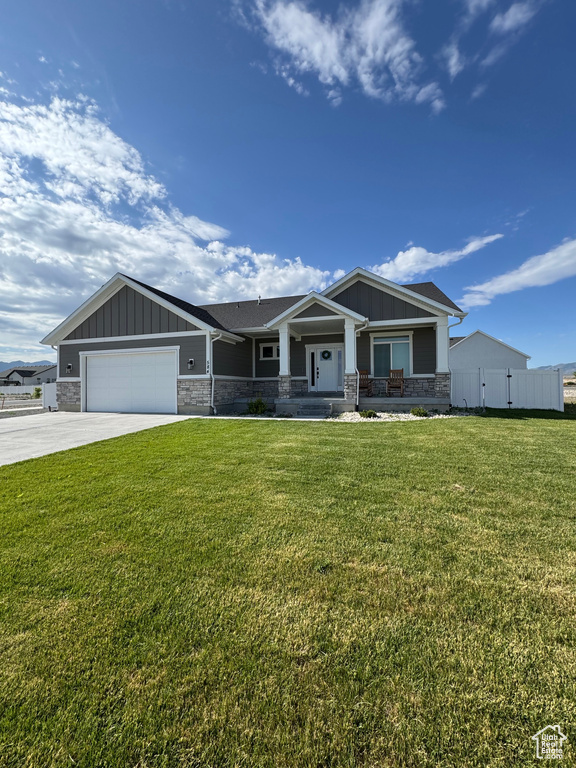 Craftsman inspired home featuring a garage, driveway, a front yard, a porch, and board and batten siding