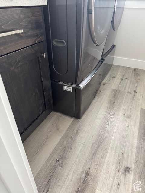 Detailed view of wood finished floors, washer and clothes dryer, and fridge