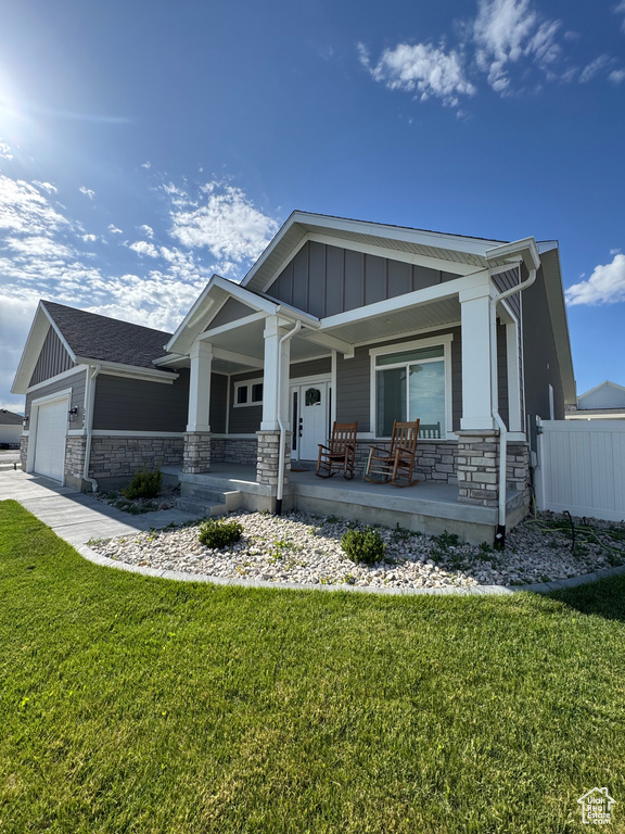 Craftsman-style home featuring board and batten siding, stone siding, covered porch, and an attached garage