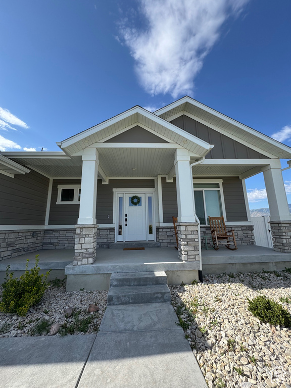 Property entrance featuring stone siding, a porch, and board and batten siding