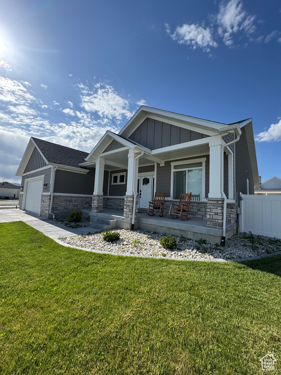 Craftsman-style house with board and batten siding, stone siding, covered porch, and a garage