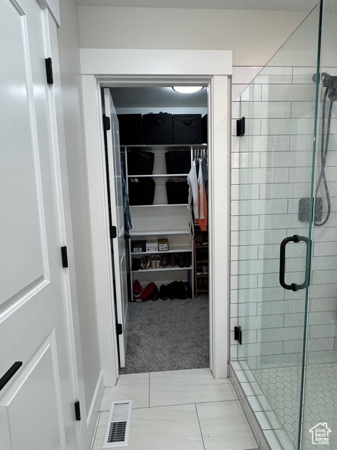 Bathroom with a walk in closet and a shower stall