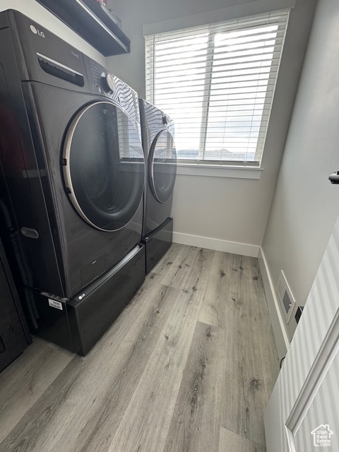 Laundry room with washer and dryer and wood finished floors