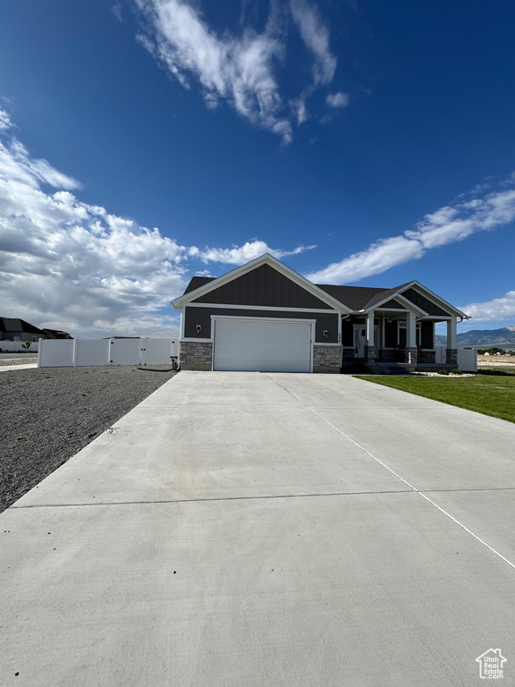 View of front of property with concrete driveway, a garage, board and batten siding, and a porch
