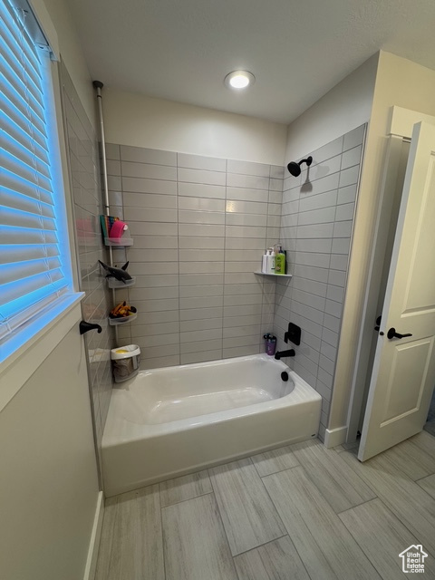 Full bathroom featuring wood finish floors and  shower combination